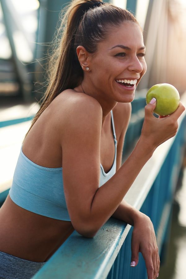 image of a woman after iv therapy enjoying an apple