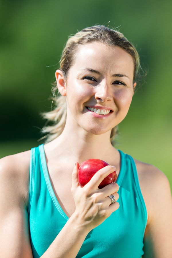 image of a woman smiling and holding an apple