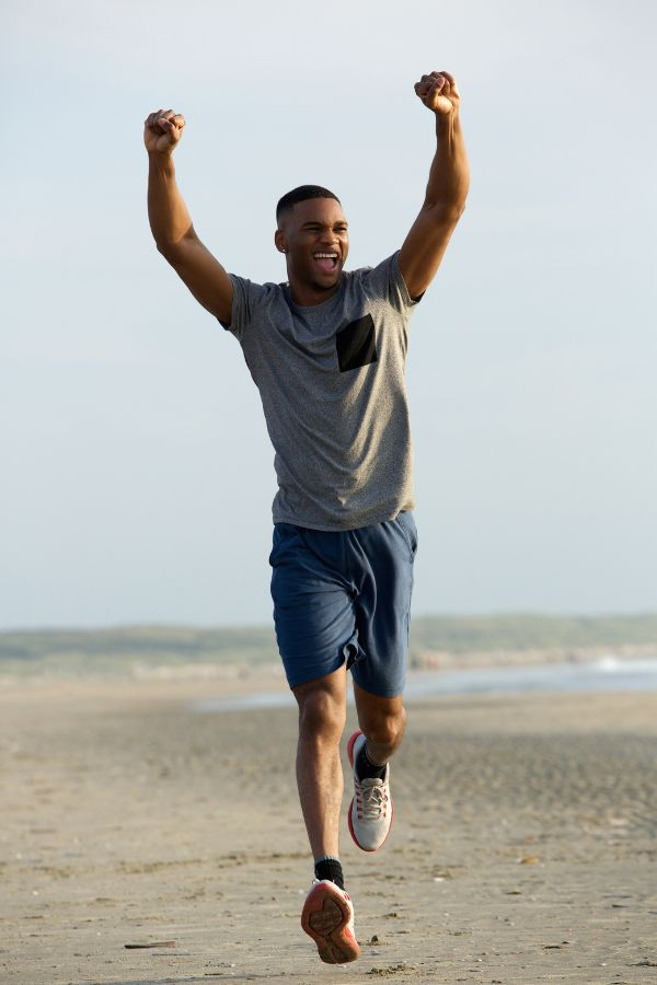 image of a man running down a beach raising his arms triumphantly